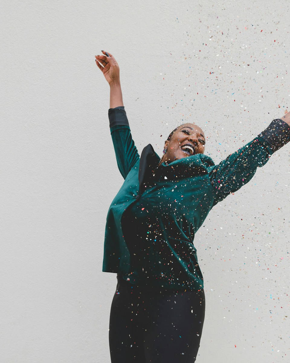 woman with life and health insurance in green jacket raising her hands