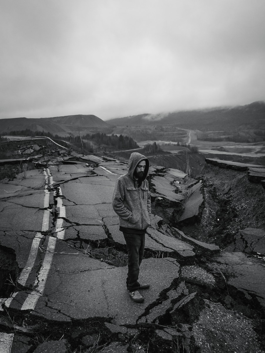 man in gray jacket with earthquake insurance standing on gray concrete road